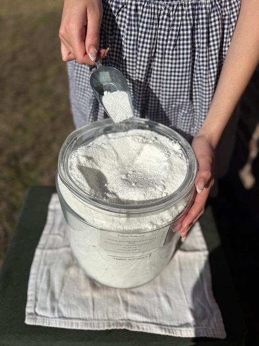 Person scooping fabric softener from a container outdoors