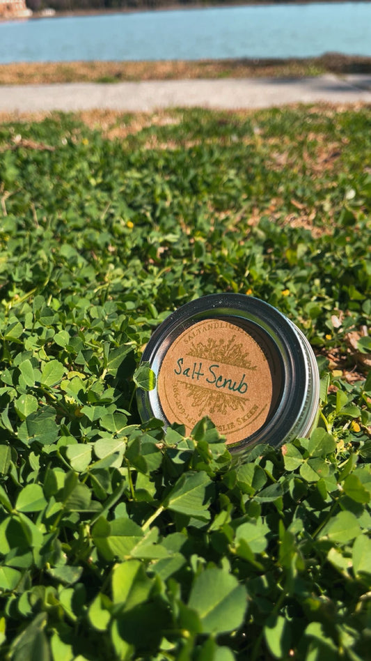 Jar of salt scrub with a brown label on green plants