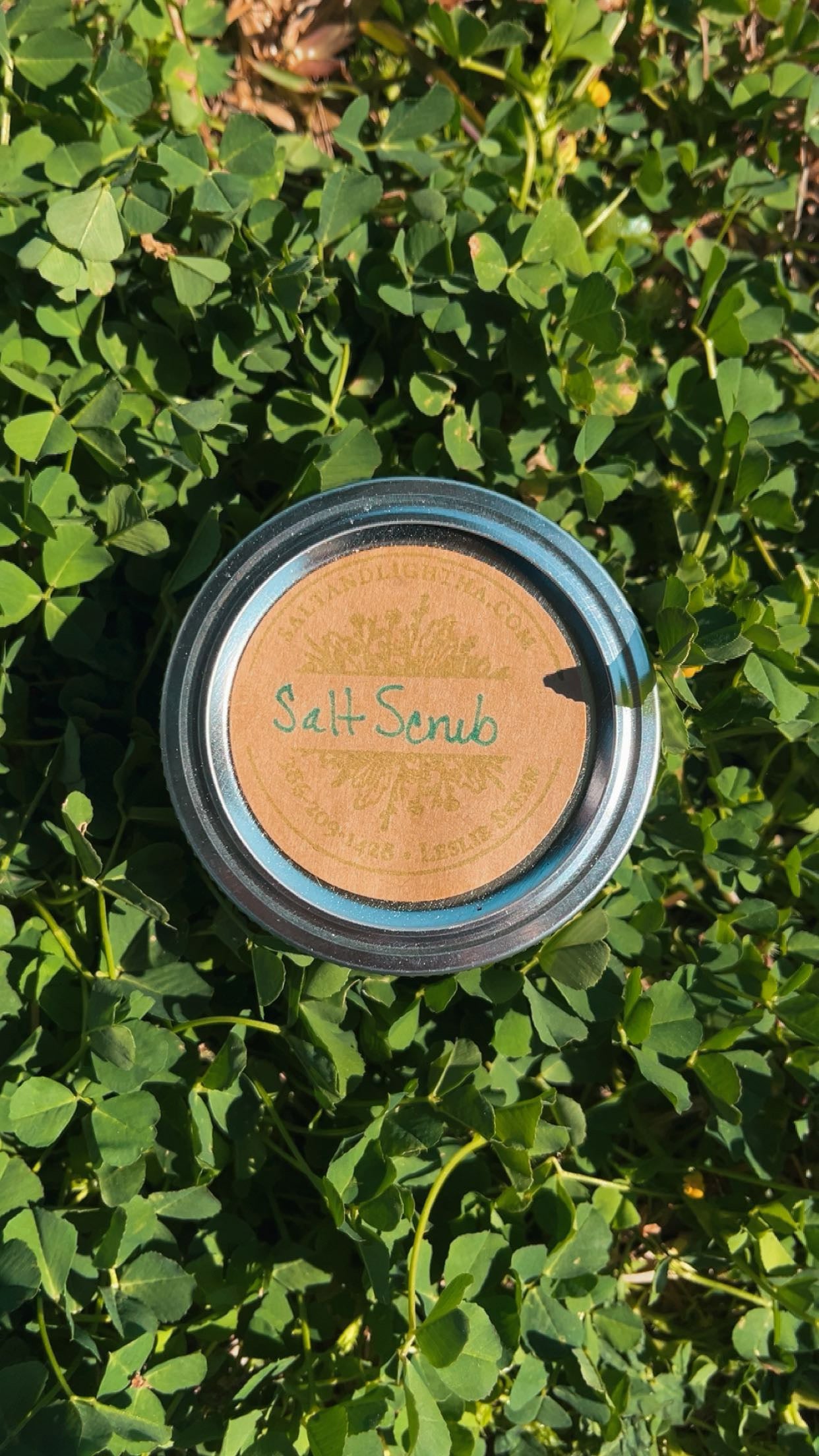Jar of salt scrub on a bed of clover leaves