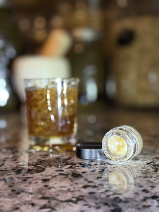 Glass of raw honey with a jar of tallow Lip balm on a marble surface