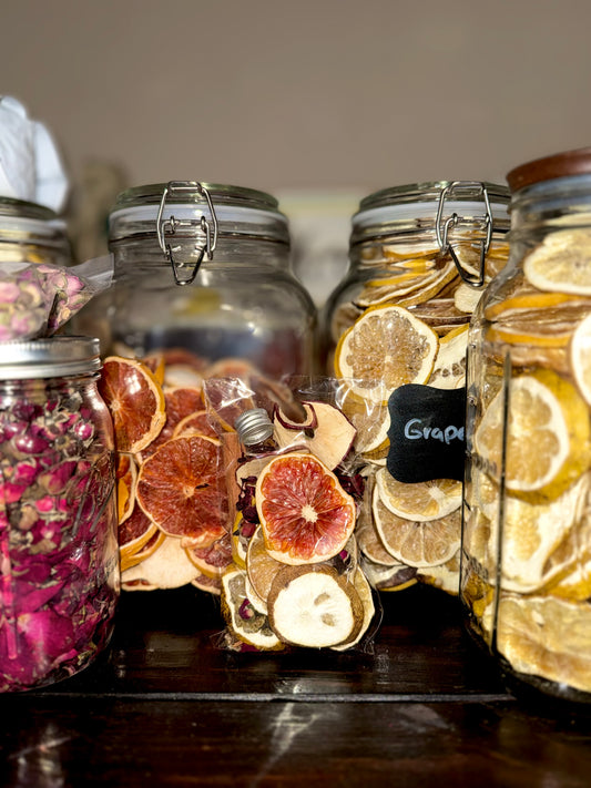 Jars filled with dried fruits and herbs on a wooden shelf.